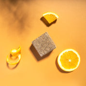 yogh hair volume and shine vegan shampoo bar with amla and orange on orange background with its ingredients