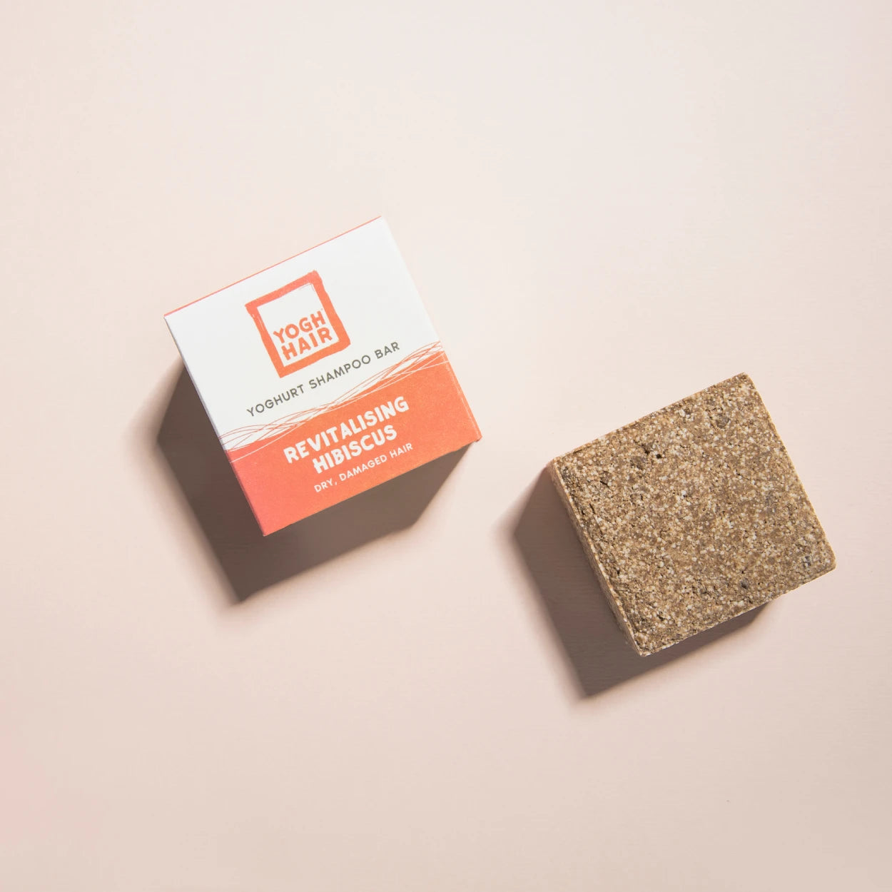 yogh hair revitalising yoghurt shampoo bar with hibiscus outside of box on pink background