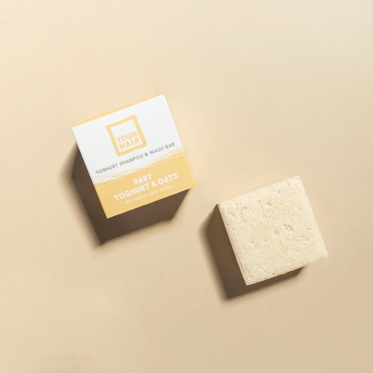 yogh hair baby shampoo bar with yoghurt and oats outside of box on beige background