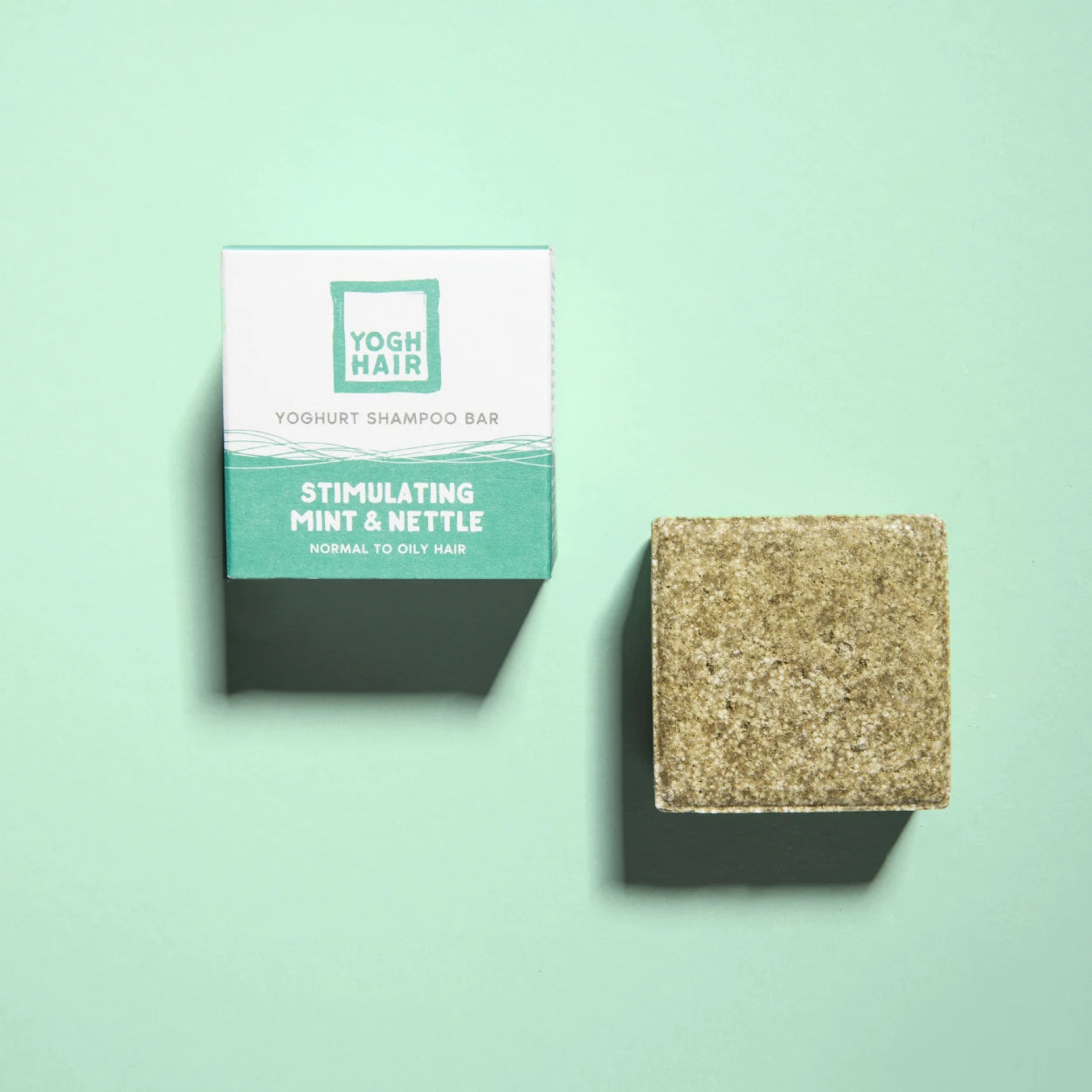 yogh hair stimulating yoghurt shampoo bar with mint and nettle outside of box on green background