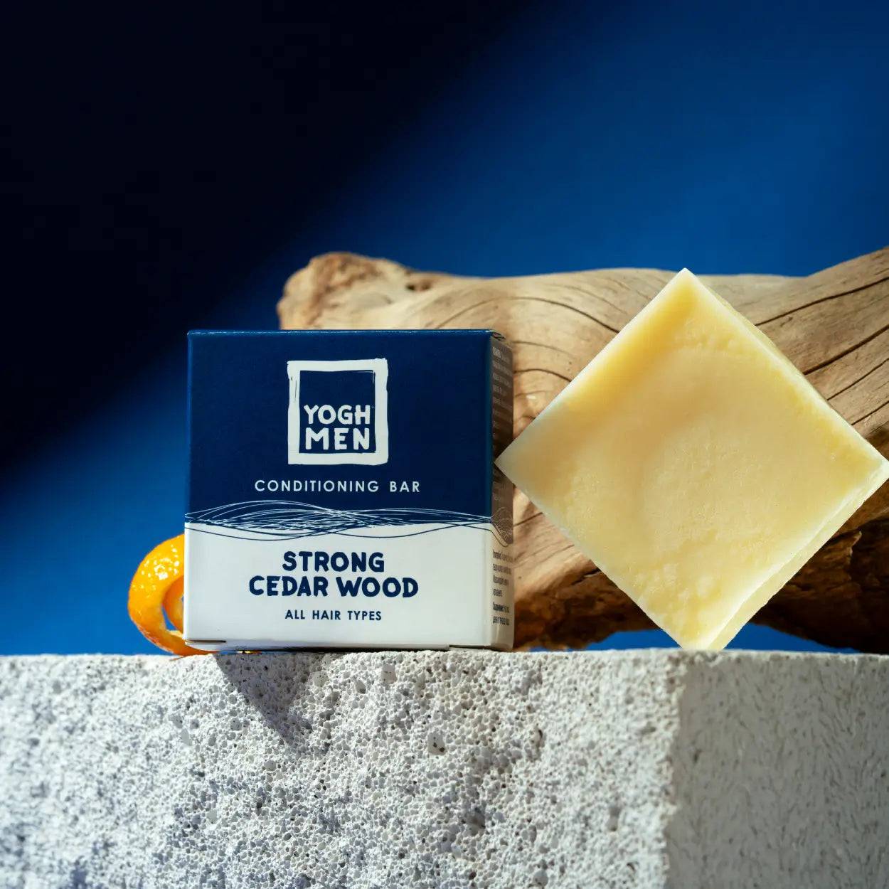 yoghmen conditioner bar for strong hair next to its packaging and active ingredients
