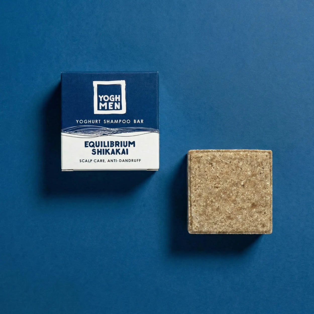 yoghmen equilibrium shampoo next to its packagin on blue background