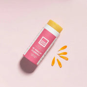 yoghskin solid makeup cleanser without its lid on a pink background next to some calendula petals